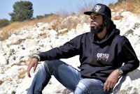a man in a black hoodie sitting on rocks