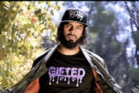 a man wearing a hat and a t - shirt with the word 'gifted' on it